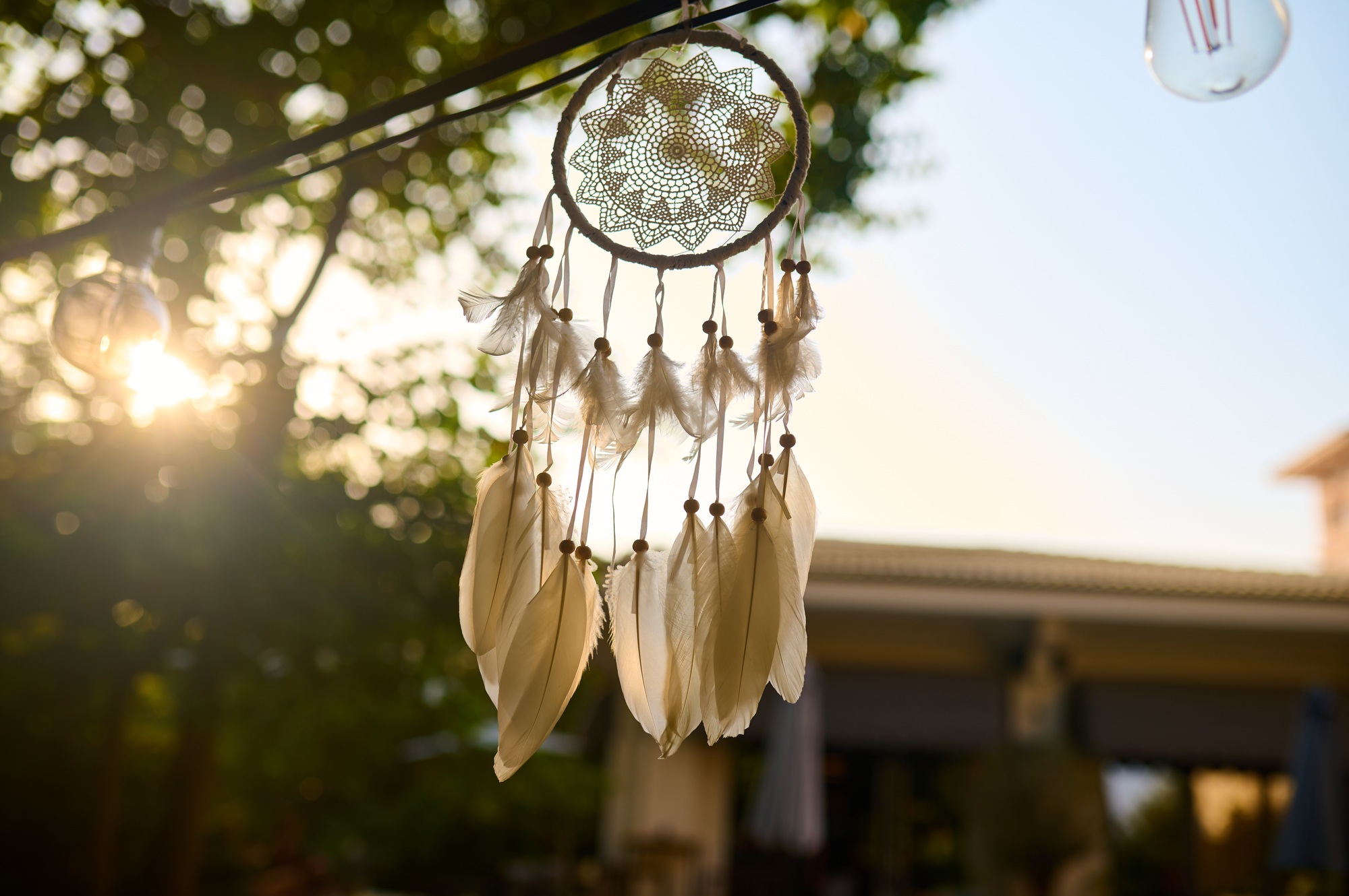Delicate dreamcatcher hangs in the warm sunlight at an outdoor space, capturing the essence of