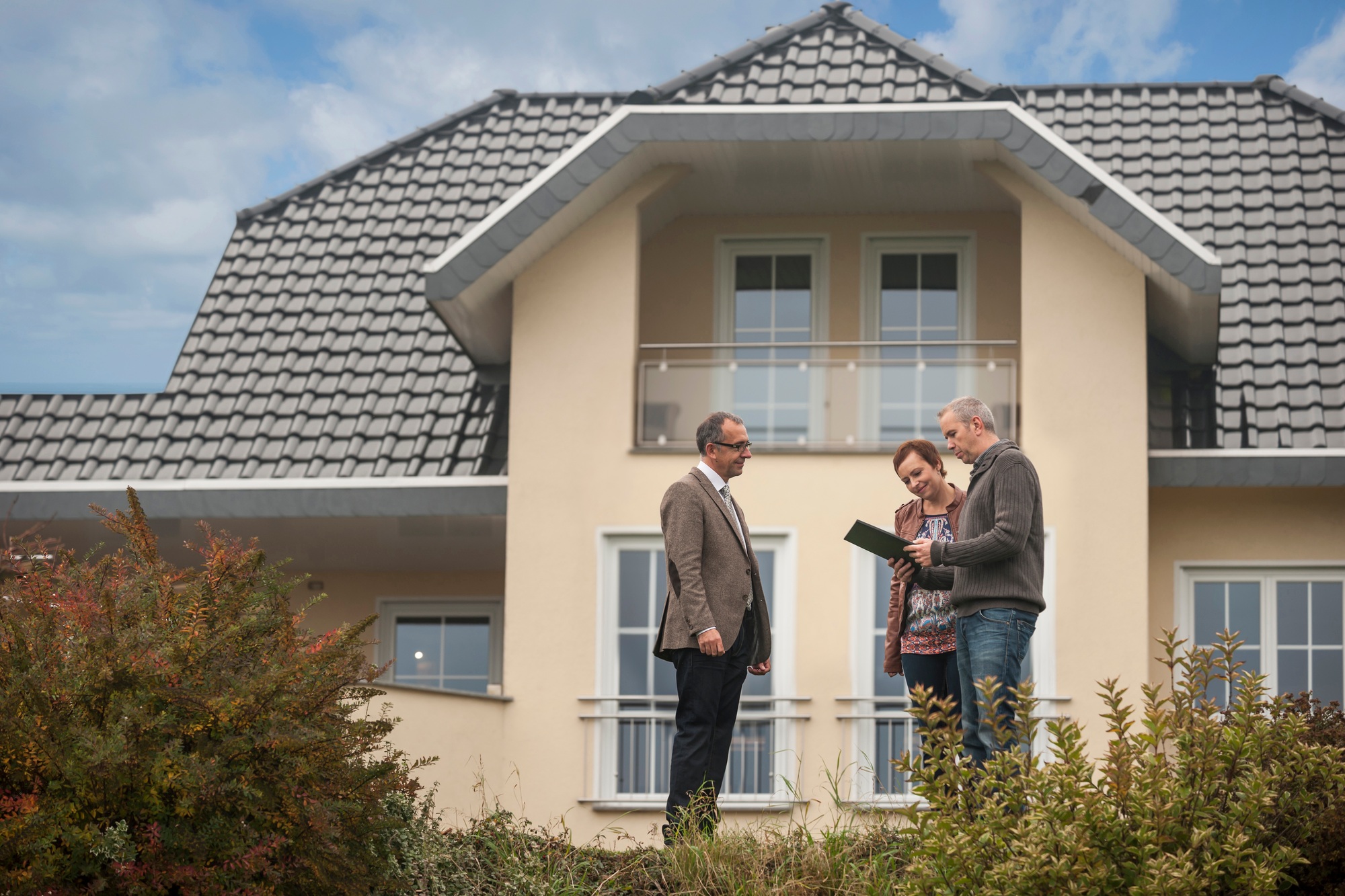 Estate agent with potential buyers in front of residential house